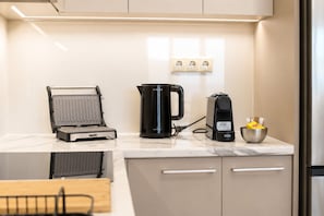 A kitchen with a waffle maker, a coffee maker, and a bowl of ingredients.