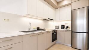 Eine moderne Küche mit einem Edelstahl-Kühlschrank, einem Backofen und einem Spülbecken mit Armatur.
