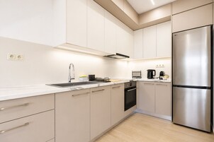 Una cocina moderna con un refrigerador de acero inoxidable, horno empotrado y un lavamanos con grifo.