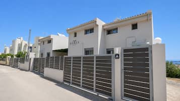 Una propiedad cercada con un letrero de Nerea Suites, con un estilo arquitectónico moderno que incluye un techo plano y vistas despejadas del entorno.