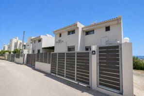 Una propietat tancada amb un rètol de Nerea Suites, amb un estil arquitectònic modern, teulada plana i una vista despejada de l'entorn.