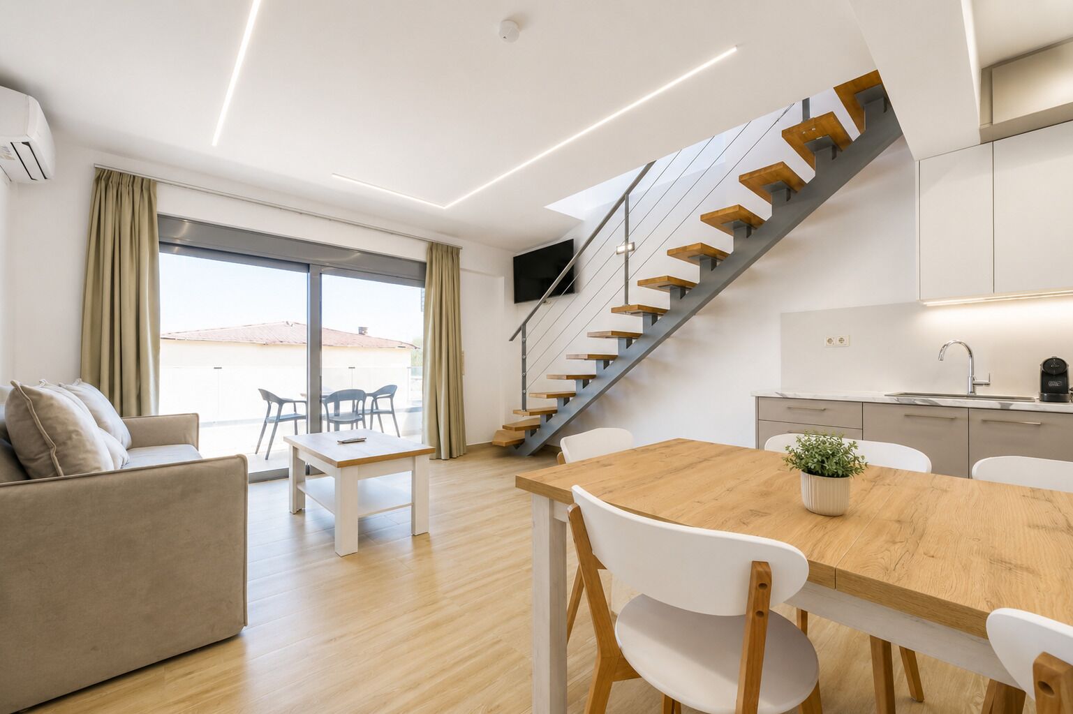 Un interior moderno con una escalera, un comedor y una cocina.