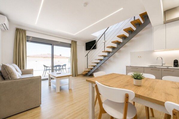 Un interior modern amb una escala, una zona de menjador i una cuina.
