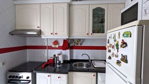 Eine Küche mit weißen Schränken, einem Herd, einer Spüle und einem Kühlschrank.