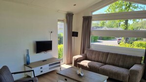 A living room with a sofa, a TV, a coffee table, and a chair. - Holiday Home in Velsen-zuid With Terrace (Velsen-Zuid)