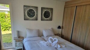 A bedroom with a bed, two nightstands, a lamp, and two wall-mounted artworks. - Holiday Home in Velsen-zuid With Terrace (Velsen-Zuid)