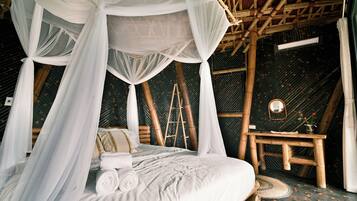 A room with a bed, a wooden ladder, a small table, and a hanging canopy.