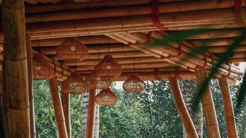 A bamboo structure with woven hanging lamps and a view of greenery outside.