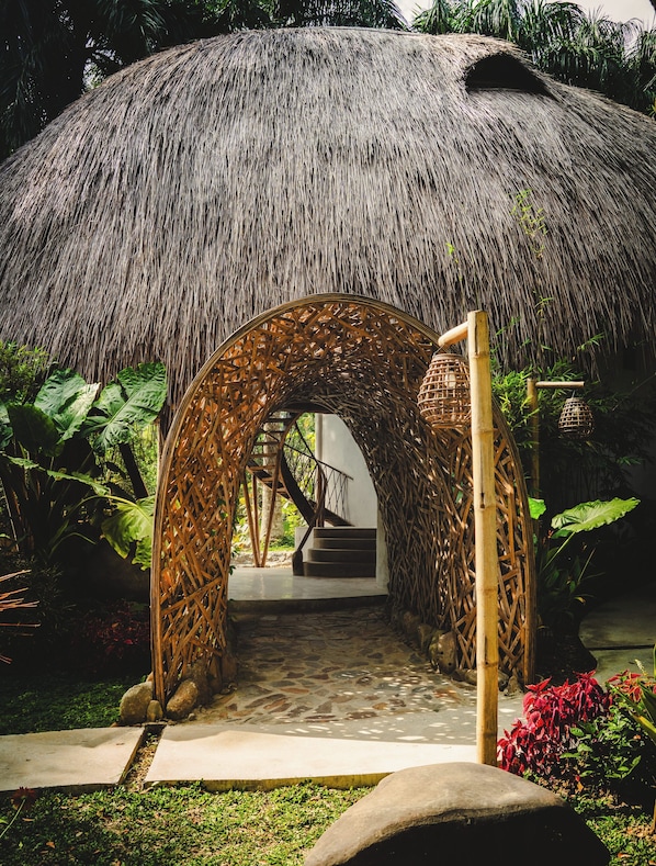 A thatched-roof structure with a wooden staircase leading to an entrance.