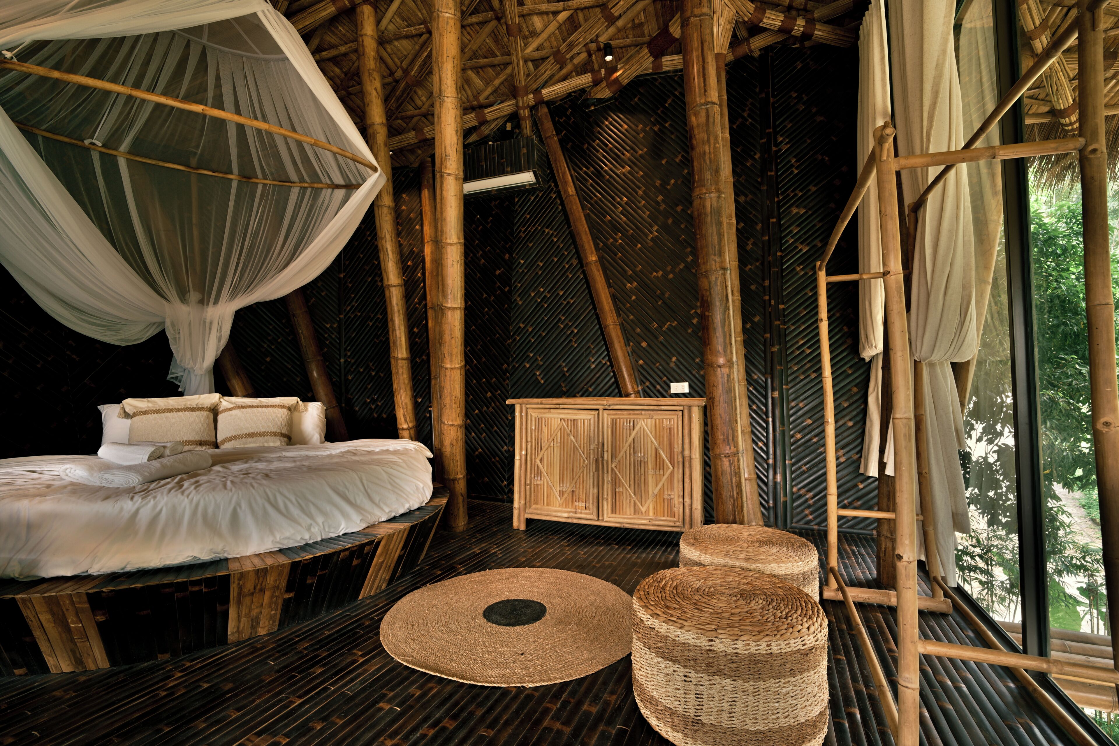 A room with a bed, a cabinet, and a large window.