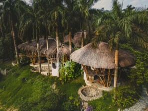 Thatched-roof huts surrounded by lush greenery and palm trees.