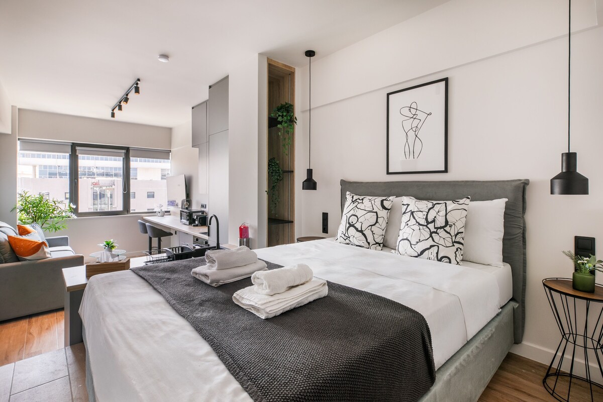 Ein modernes Hotelzimmer mit einem großen Bett, einem Schreibtisch und Blick auf die Stadt.