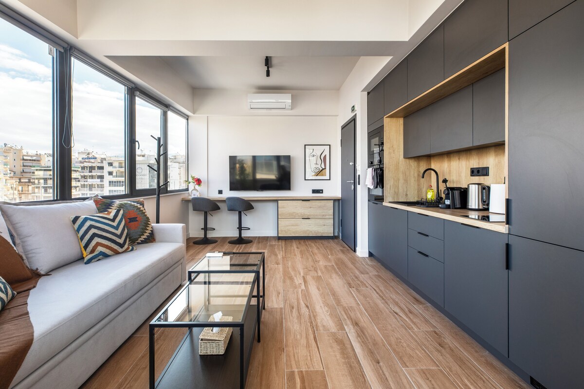 Eine moderne Wohnung mit Sofa, Fernseher, Küche und großen Fenstern.