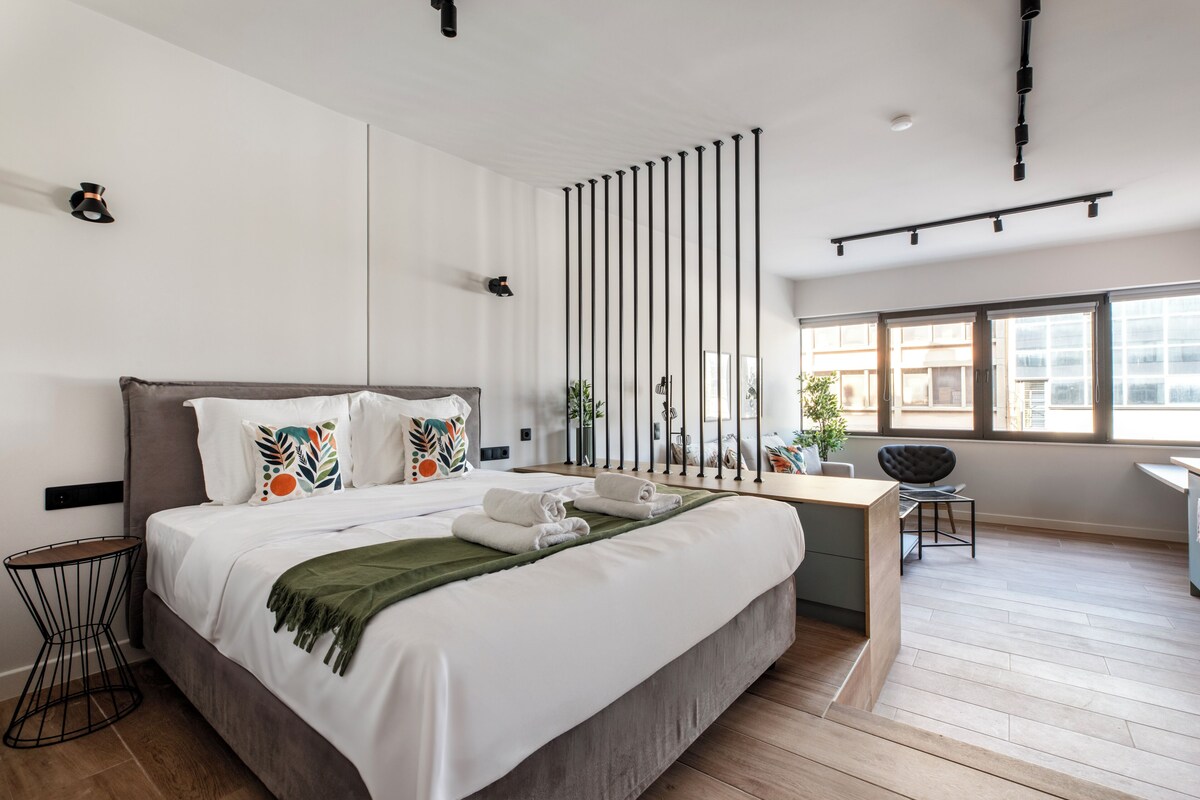 Ein modernes Hotelzimmer mit einem großen Bett, einem Schreibtisch und Blick auf die Stadt.