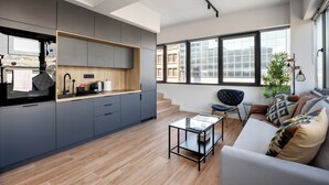 A modern kitchen with grey cabinets, a wooden countertop, and a built-in oven. - Nest Athens Retreat Studios (Tavros)