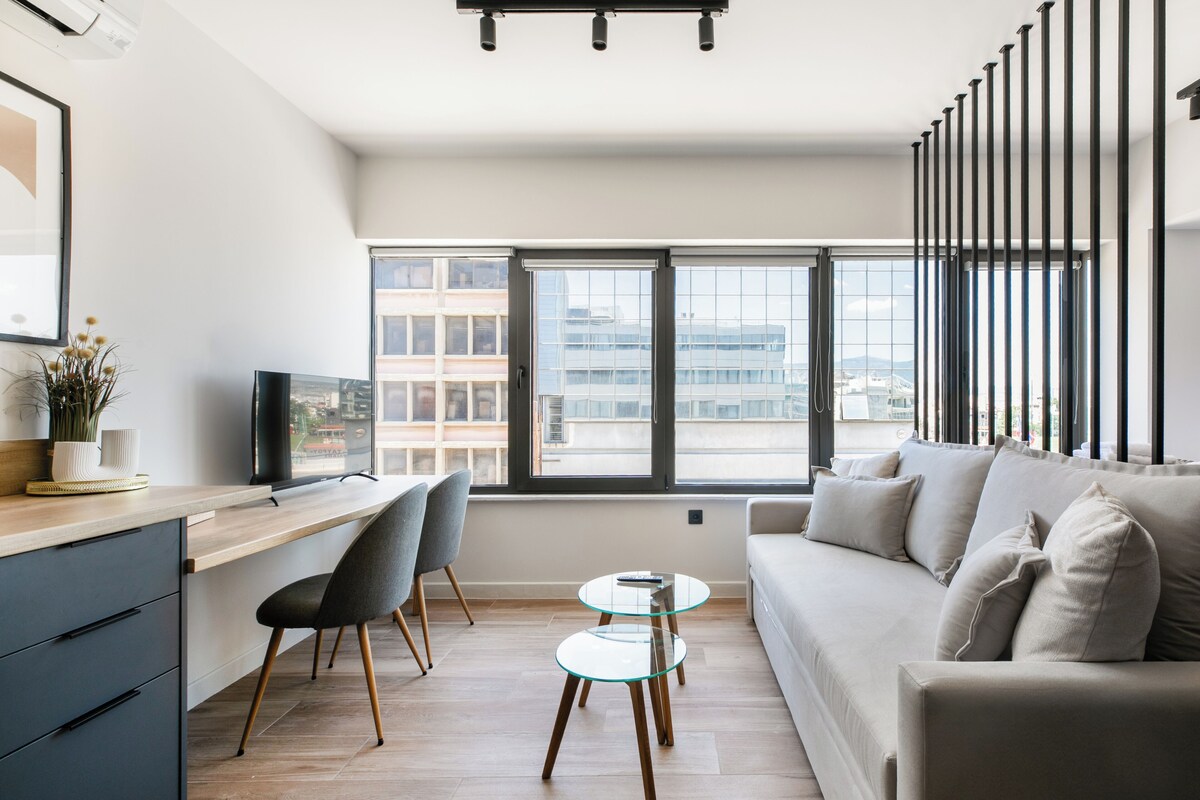 Ein modernes Wohnzimmer mit einer Couch, einem Esstisch, Stühlen und einem Fernseher.