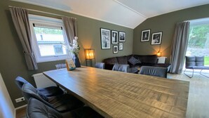 A dining area with a long table, chairs, a sofa, and framed pictures on the wall. - Holiday Home in Maarn With Terrace (Maarn)