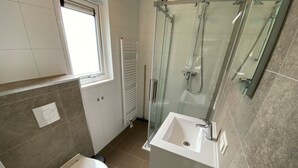 A bathroom with a toilet, a sink, a glass shower enclosure, and a window. - Holiday Home in Maarn With Terrace (Maarn)