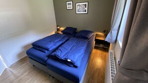 A bedroom with a bed, two bedside tables, a window with curtains, and two framed pictures on the wall. - Holiday Home in Maarn With Terrace (Maarn)