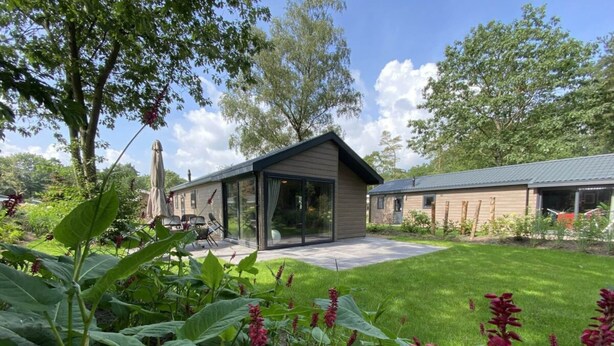 A modern house with a large glass door, a patio, and a well-maintained garden. - Holiday Home in Maarn With Terrace (Maarn)