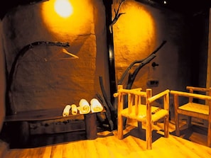 A rustic interior with a stone fireplace, wooden chairs, and a tree branch decoration.