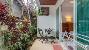 A small patio with a table and chairs, surrounded by plants and a glass door leading to an interior space. - Relaxing 1BR Close to Beach & Lake- relife C200 (Tambon Rawai)