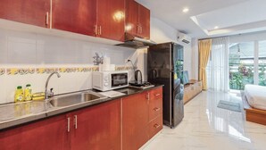 A modern kitchen with stainless steel appliances, wooden cabinets, and a large window offering a view of greenery. - Relaxing 1BR Close to Beach & Lake- relife C200 (Tambon Rawai)
