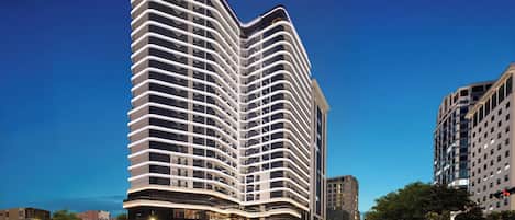 A high-rise hotel with a curved facade, multiple balconies, and a prominent signage at the top.