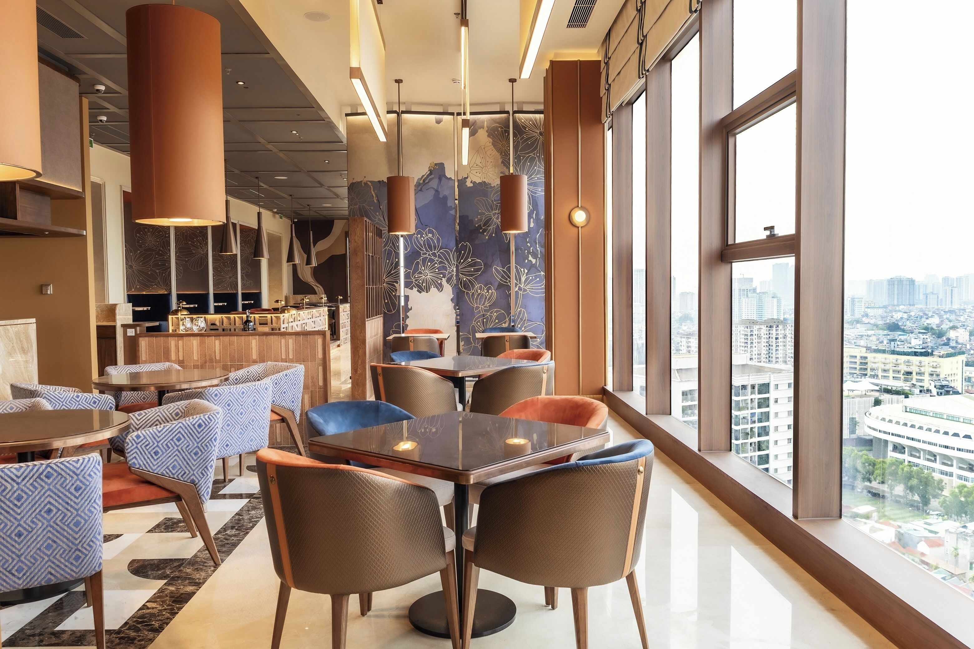 A modern hotel interior with a bar area, dining tables, and chairs, and a city view through large windows.