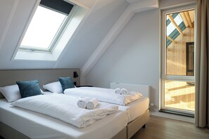 A modern hotel room with a sloped ceiling, skylight, large windows, and a view of the building's exterior. - Ten-bedroom Group Villa Near the Shores (Nieuwvliet)