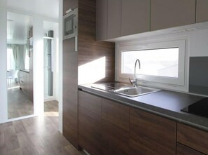Eine moderne Küche mit Fenster, Edelstahl-Spüle und Holzschränken.
