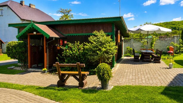 A rustic building with a green roof, a wooden bench, and a paved patio area. - Cottage for 4 People, Wapnica (Międzyzdroje)