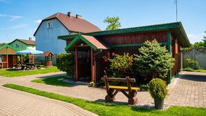A rustic building with a wooden exterior, a paved pathway, and a bench. - Cottage for 4 People, Wapnica (Międzyzdroje)
