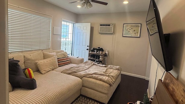 A living room with a sectional sofa, a ceiling fan, a TV mounted on the wall, and a patterned rug. - 1 Bed, 1 Bath - Fully Furnished Modern Del Rey Home (Los Angeles)