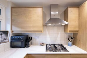 Eine Küche mit Holzschränken, einer Bosch-Dunstabzugshaube, einem Herd und einem Backofen.