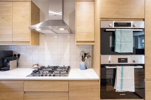 Una cucina moderna con piano cottura, forno e cappa aspirante Bosch in acciaio inox.