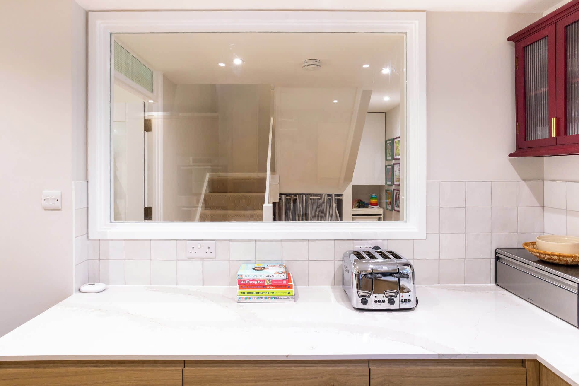A kitchen with a large window, a toaster, and a box of cooking books on the counter.