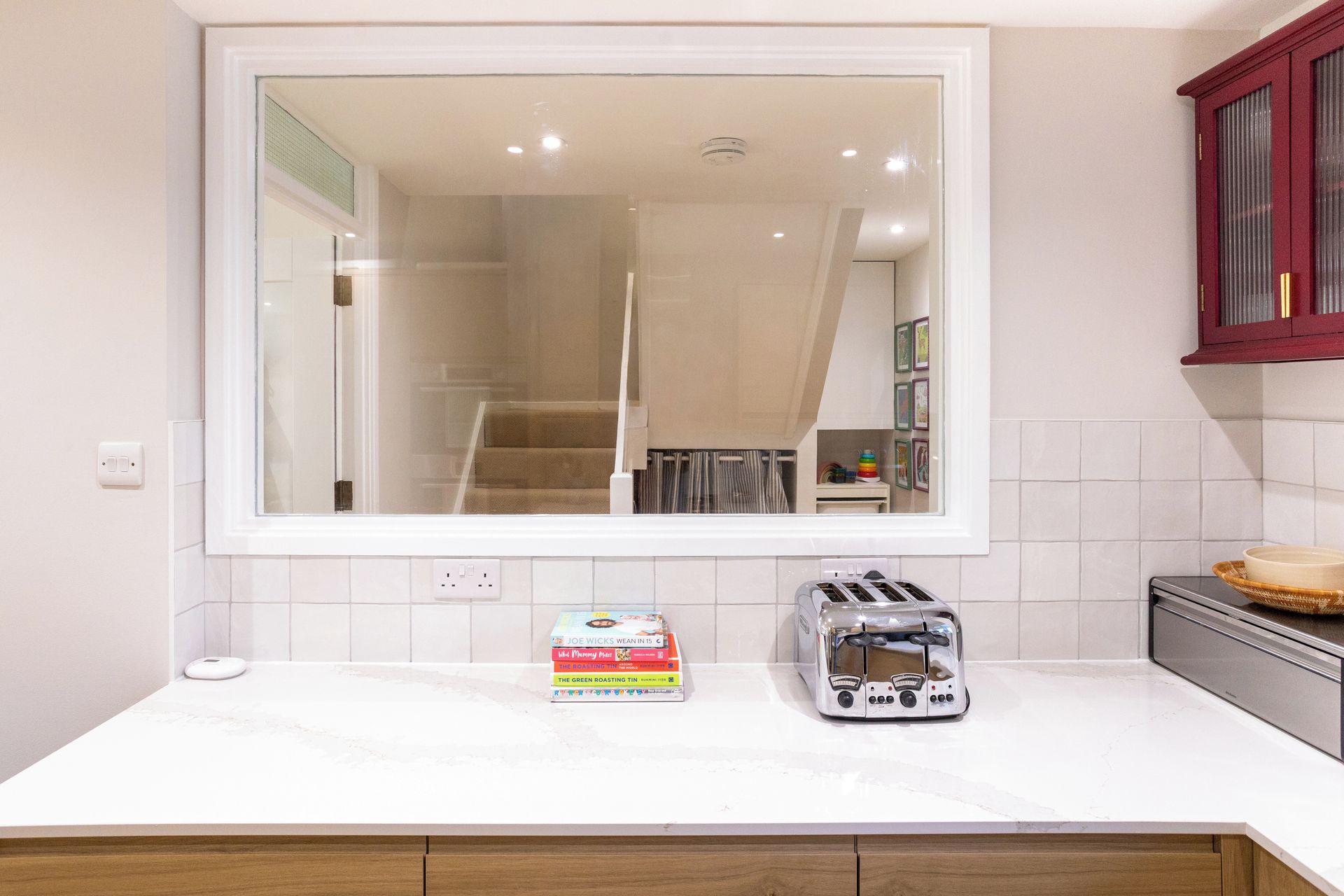 A kitchen with a large window, a toaster, and a box of children's books on the counter.