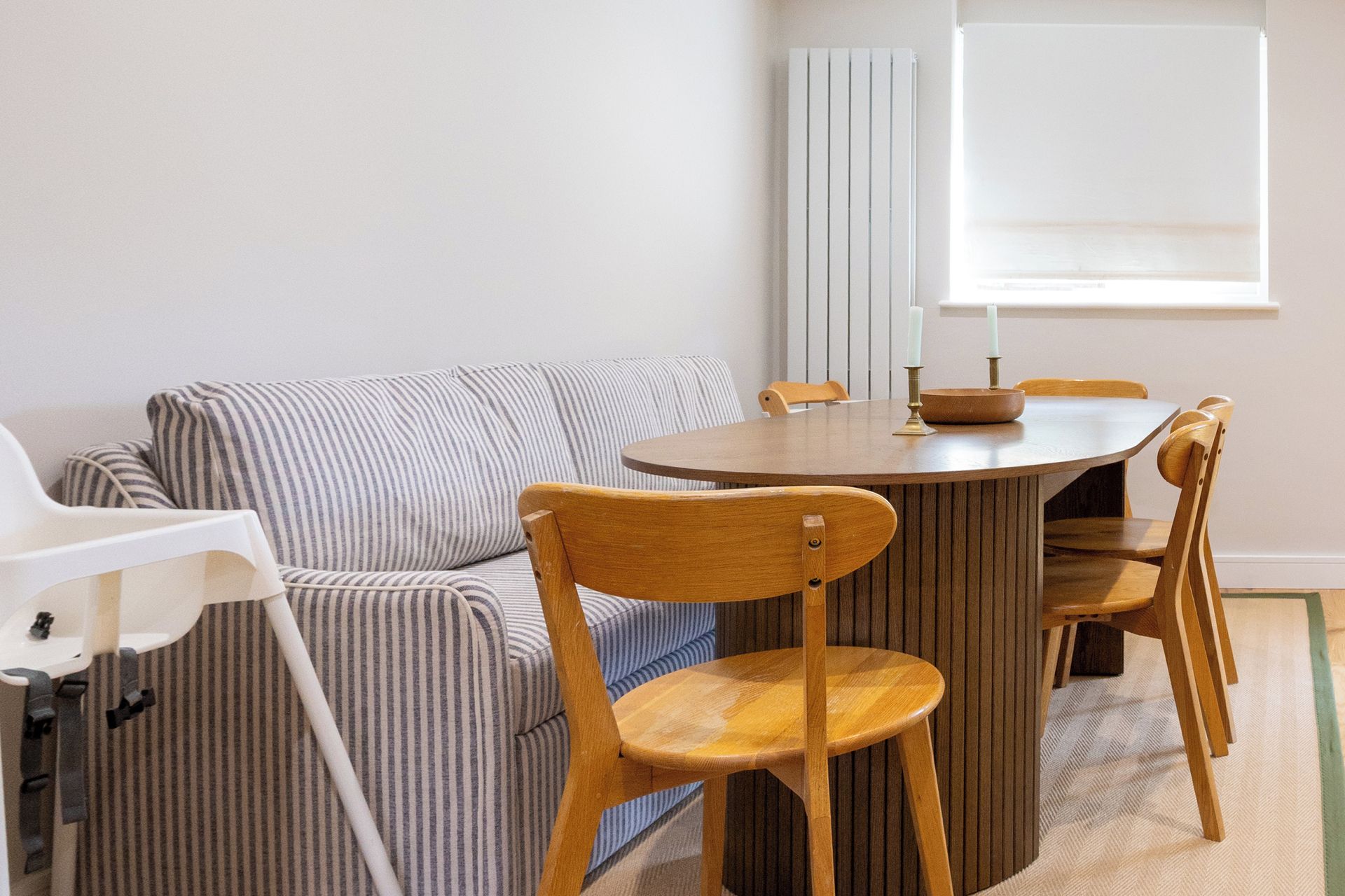 Une pièce avec une table ronde en bois, un canapé à rayures et deux chaises en bois.