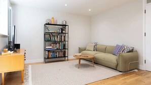 Un salon comprenant un canapé, une table basse, une bibliothèque et un bureau avec un ordinateur.
