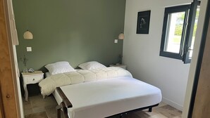 Ein Schlafzimmer mit einem Bett, zwei Nachttischen, einem Fenster und einer Tür.