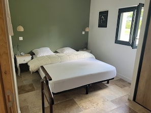 A bedroom with a bed, two bedside tables, a window, and a door. - A lovely house with a private pool, in a quiet location, 20 minutes from Lyon (Dardilly)