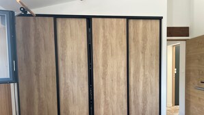 Ein Zimmer mit einer verschiebbaren Holzwand, einer Metalltür und einem Fliesenboden.