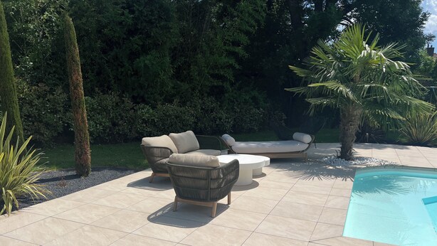 Eine Terrasse mit Pool, Gartenmöbeln und einem gepflegten Garten.