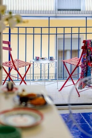 A balcony with red chairs and a small table, a railing, and a building in the background. - Bellamore (PIANO DI SORRENTO)