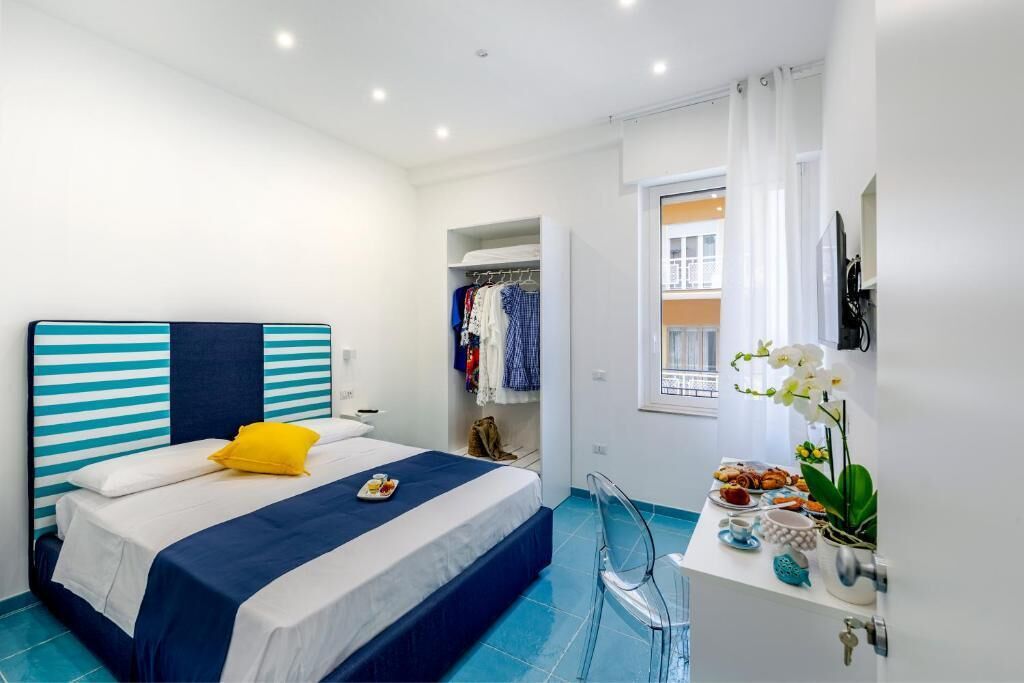 A bedroom with a bed, a desk with a chair, a wardrobe, and a window with curtains.