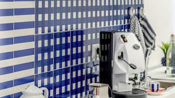 Une cuisine équipée d’une machine à café, avec une pomme rouge et un crédence à carreaux.
