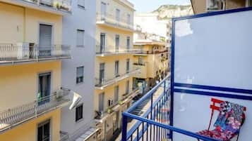 Una calle estrecha flanqueada por edificios, una barandilla de metal azul y una silla.
