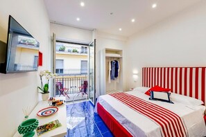 A bedroom with a bed, a small table with a vase and a plate, a mirror, and a balcony with a railing. - Bellamore (PIANO DI SORRENTO)
