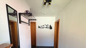 Un couloir avec un banc, un porte-manteau, un miroir et un motif décoratif sur le mur.